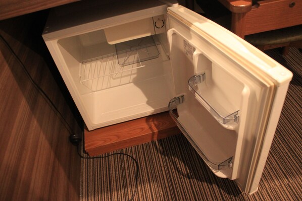 An open refrigerator with a built-in ice maker, located in a kitchen with wooden flooring and a carpeted area.