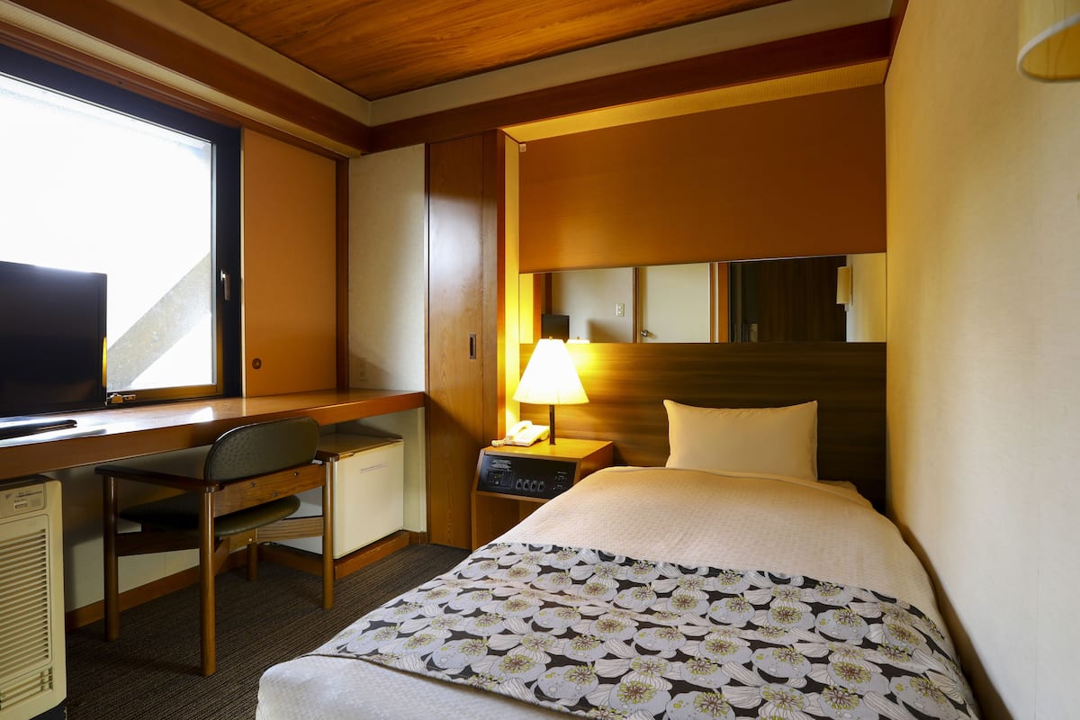 Une chambre d’hôtel comprenant un lit, un bureau avec une chaise, une lampe et un téléviseur.