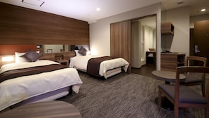 Habitación de hotel con dos camas, un escritorio, una silla y un armario.