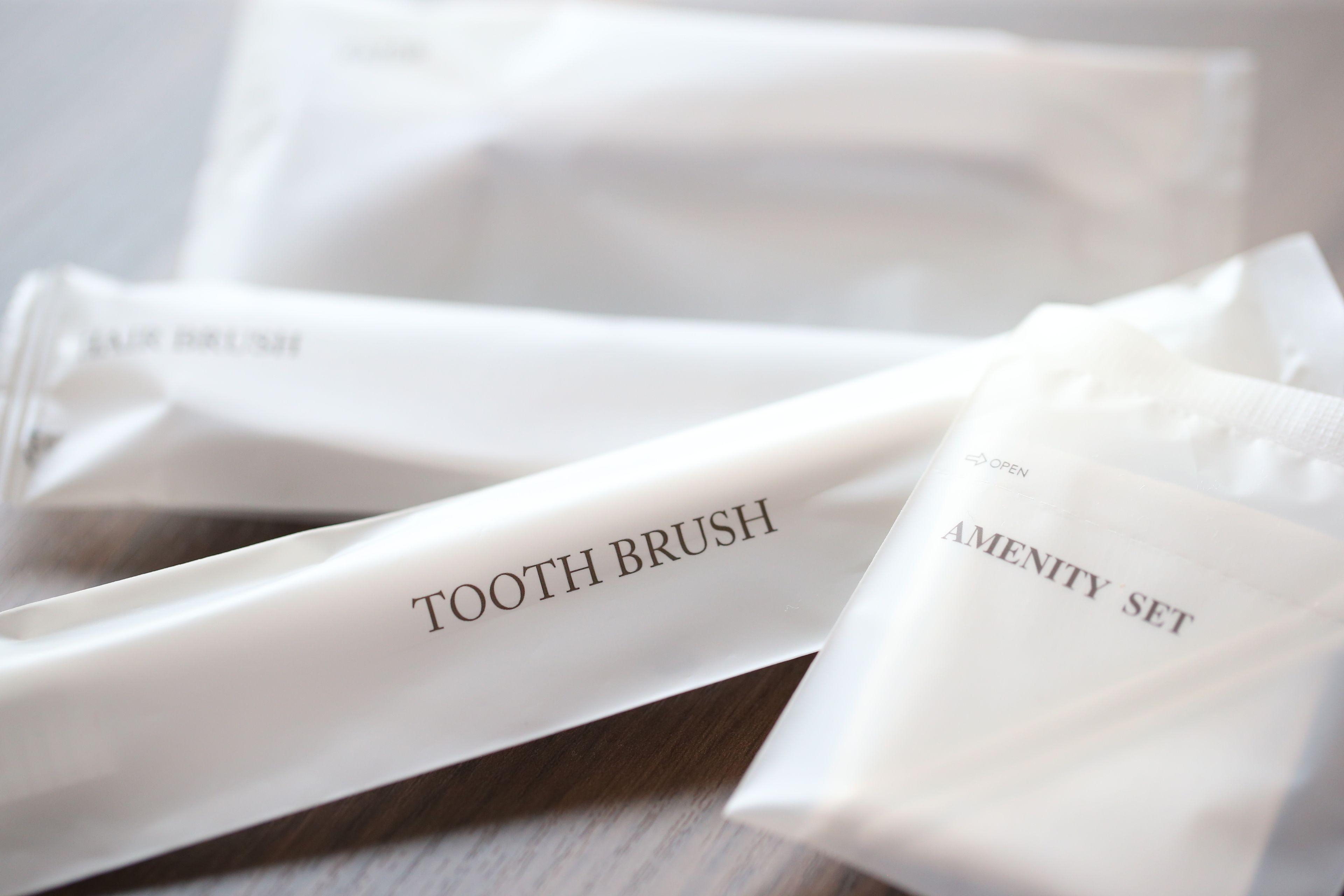 Un juego de cepillos de dientes blancos y un estuche con etiquetas que dicen "TOOTH BRUSH" y "AMENITY SET".