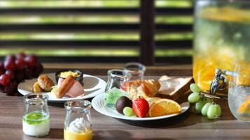 A breakfast setting with plates of food, a glass pitcher, and a bottle of orange juice.
