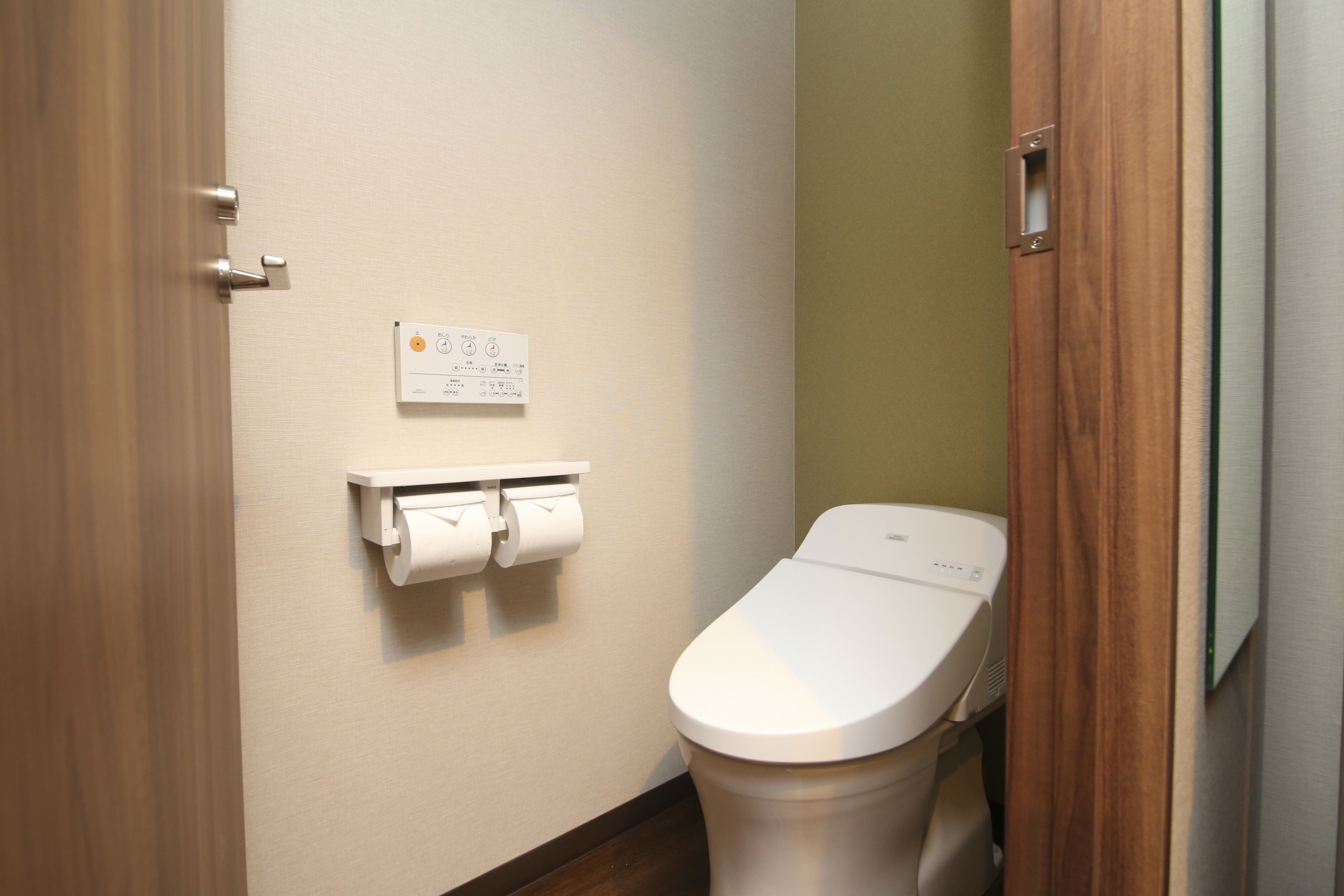 A small, clean bathroom with a toilet, a paper towel dispenser, and a sign on the wall.