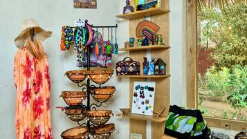 A display of woven baskets, colorful jewelry, and a tropical-themed dress in a shop setting.