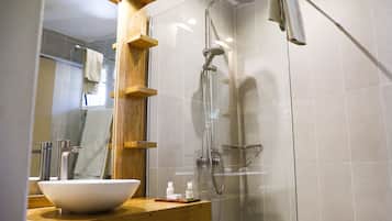 A modern bathroom with a glass-enclosed shower, a wooden vanity with a large white basin, and a mirror with wooden accents.