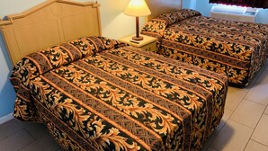 Deux lits avec une parure de lit assortie, une table de chevet avec une lampe et une fenêtre avec des rideaux.