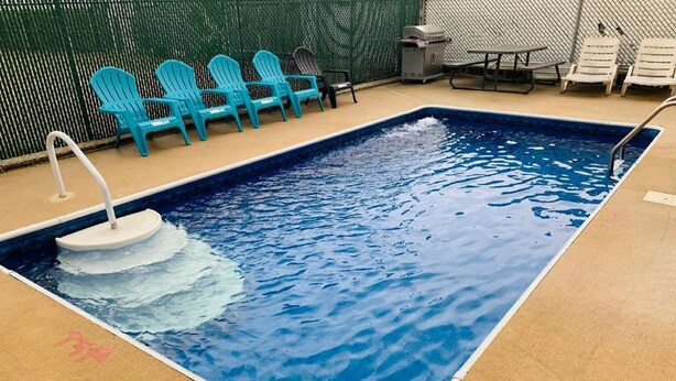 Une piscine rectangulaire dotée d’un plongeoir et de chaises longues.