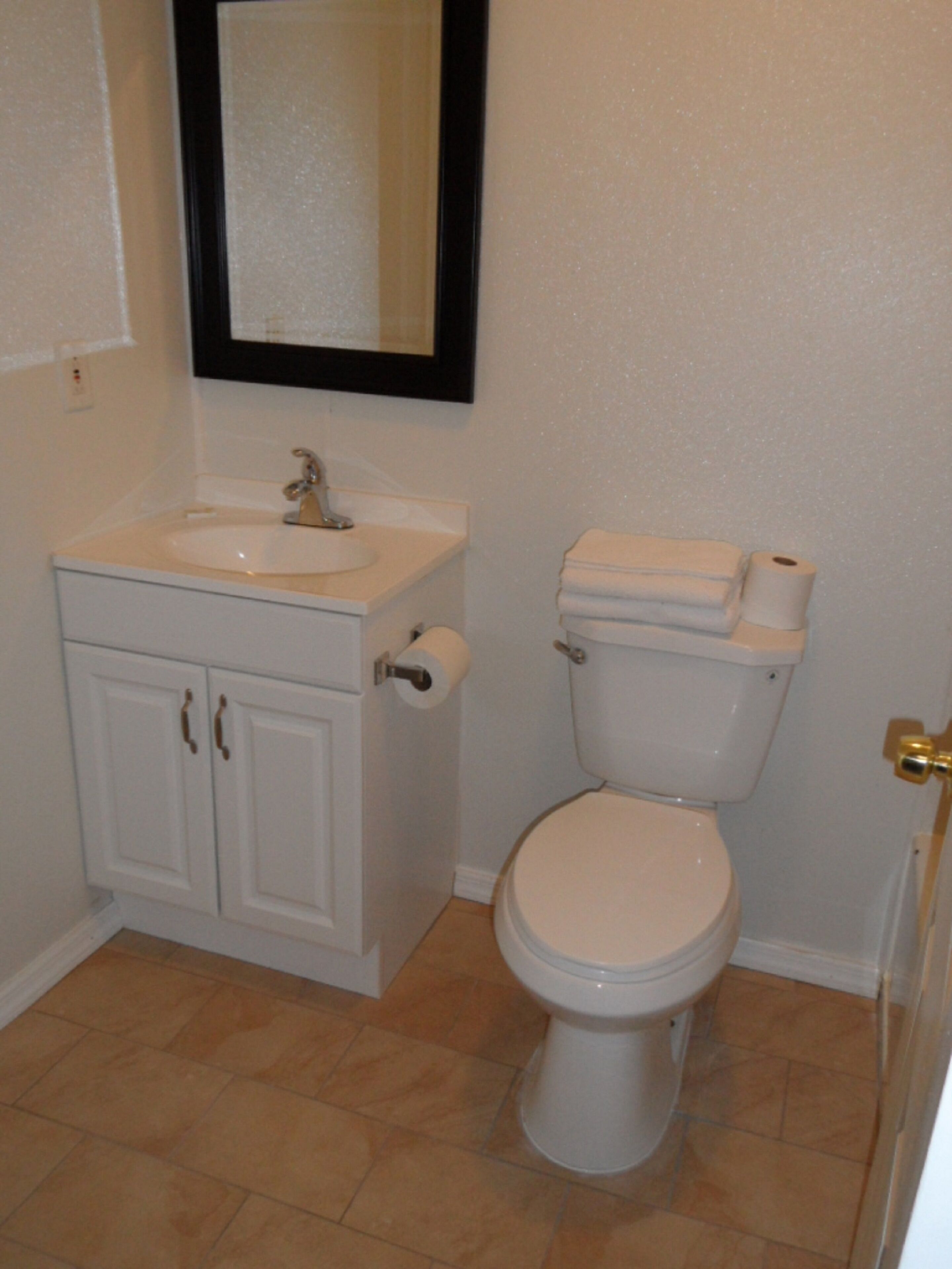 Une salle de bain avec un lavabo blanc, des toilettes et un miroir au-dessus du lavabo.