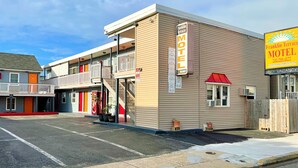 Un motel avec un panneau indicateur, un balcon et un parking.