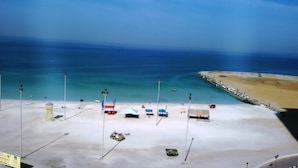 A beach with tents and a lifeguard tower. - Al Smou Hotel Apartments (Ajman)