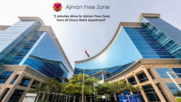 A modern building with reflective glass facades and a central flagpole. - Al Smou Hotel Apartments (Ajman)