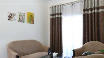 A living room with two beige sofas, a glass coffee table, and a painting on the wall.
