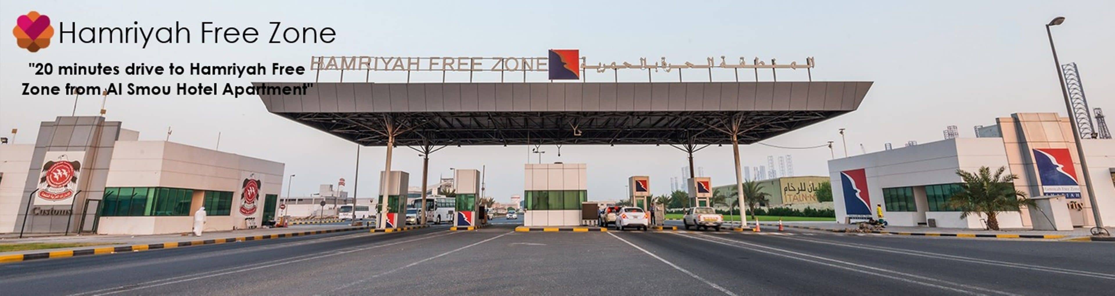Eine Mautstelle mit einem Schild für die Hamriyah Free Zone, das anzeigt, dass die Al Sou Hotel Apartment in 20 Fahrminuten erreichbar ist.