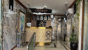 A hotel lobby with a marble floor, a central chandelier, and a reception desk. - Al Smou Hotel Apartments (Ajman)
