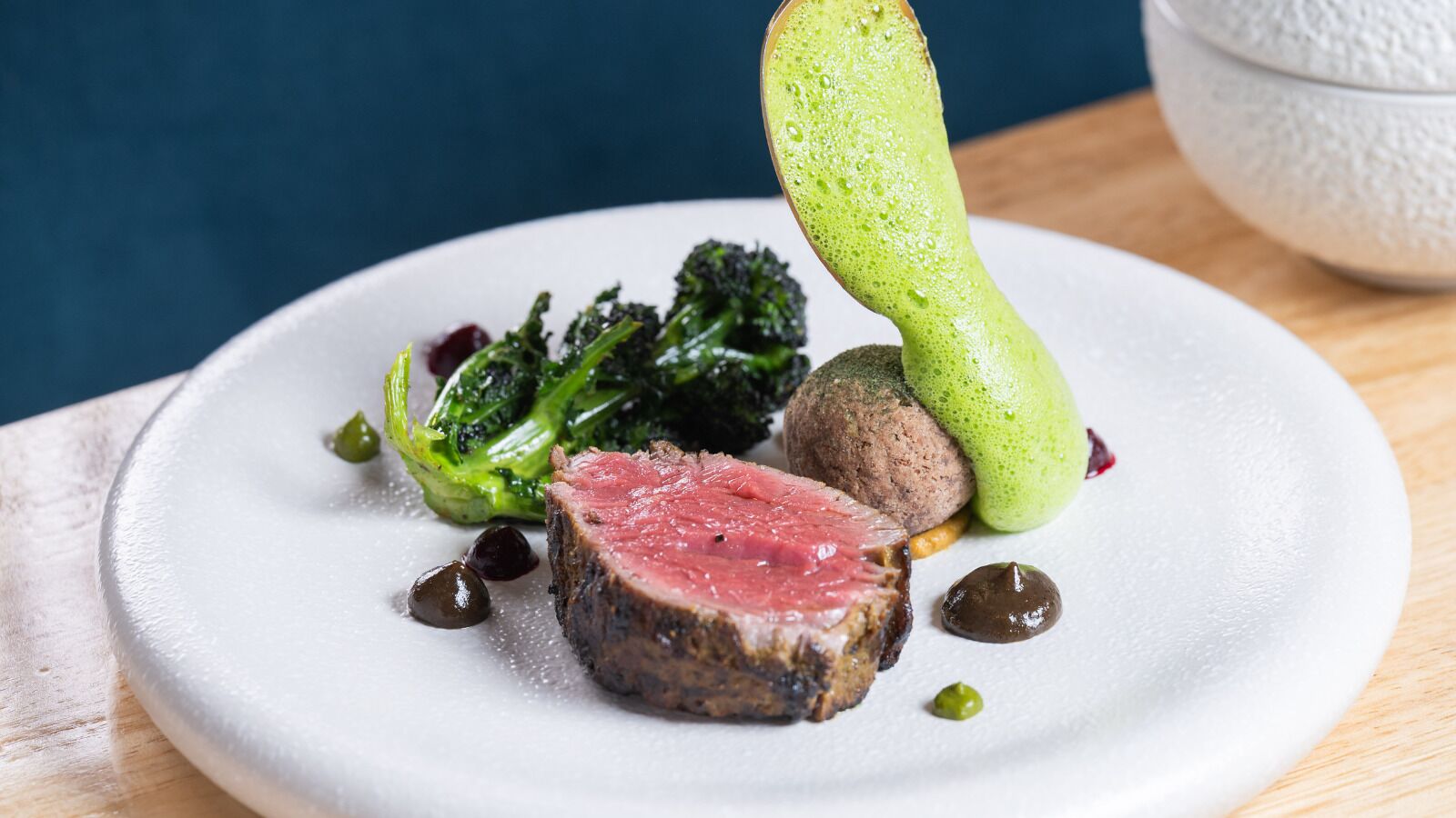 Un plato con una porción de carne, brócoli y un vegetal verde.