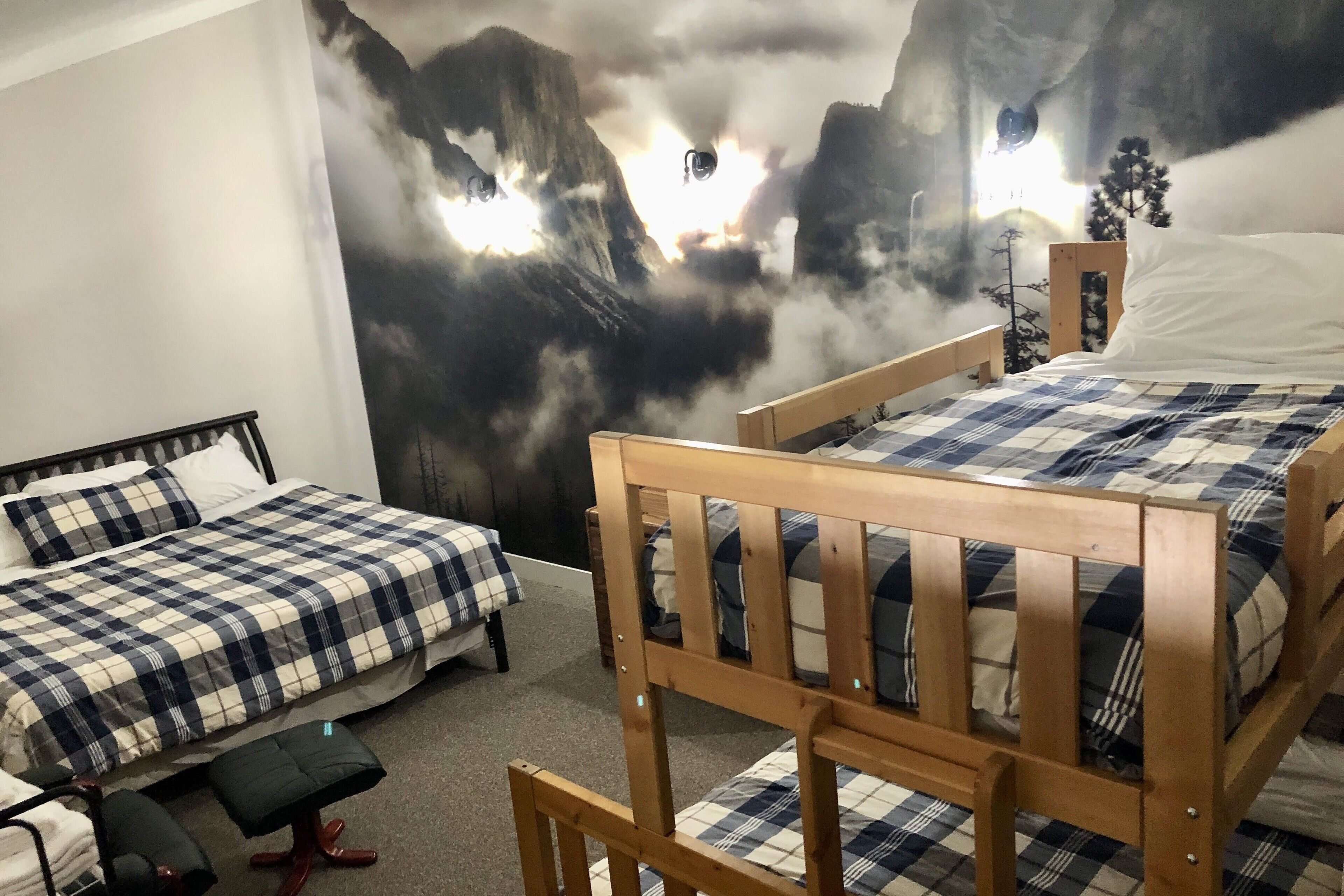 A bedroom with two beds, a bench, and a mural of mountains.