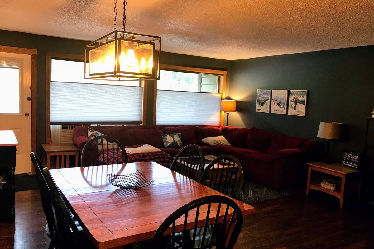 Un coin repas avec une table et des chaises en bois, un canapé rouge et un lustre.