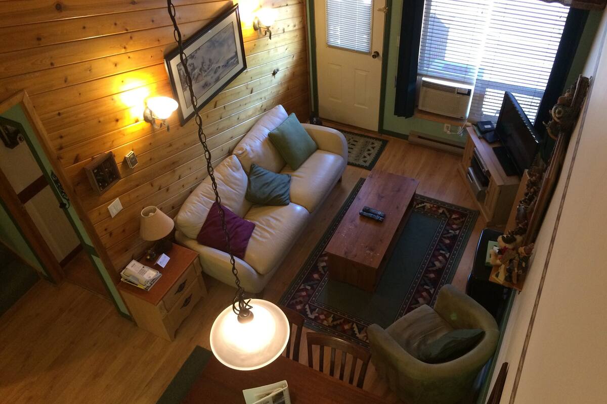 Une pièce chaleureuse avec un mur en bois, un canapé, une table basse, une lampe et un fauteuil.