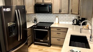 Une cuisine moderne équipée d’appareils électroménagers en acier inoxydable, d’un four à micro-ondes, d’un four et d’un évier.