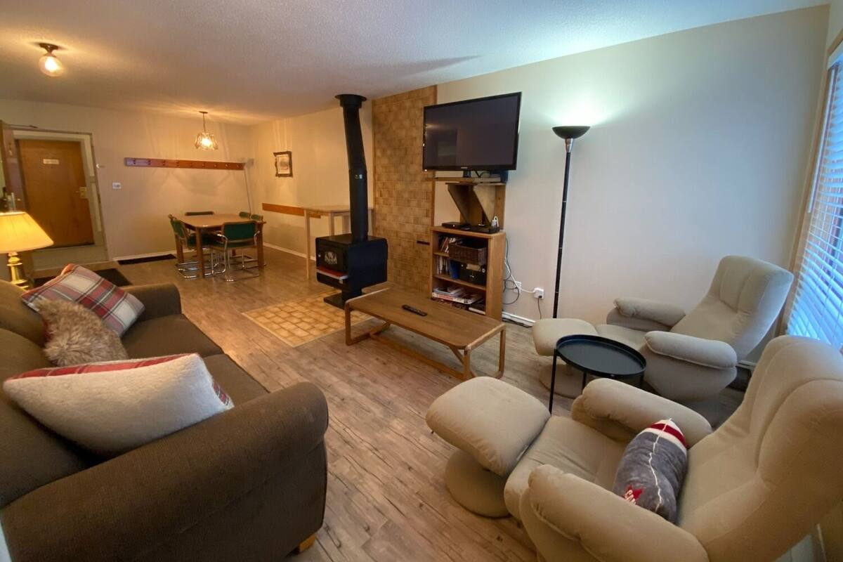Un salon chaleureux avec une cheminée, des sièges confortables, un téléviseur à écran plat et un coin repas.