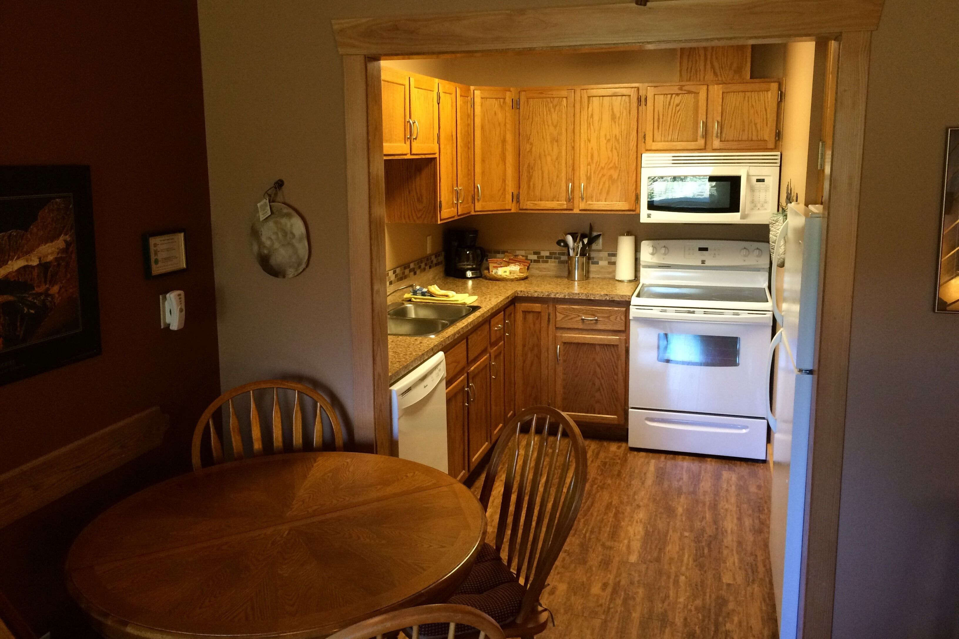 A compact kitchen with wooden cabinets, a microwave, a stove, and a dishwasher.