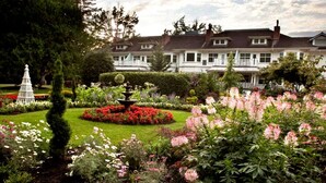 A large house with a well-maintained garden featuring a fountain, various flower beds, and a neatly trimmed lawn. - Crown Mansion Boutique Hotel & Villas (Qualicum Beach)