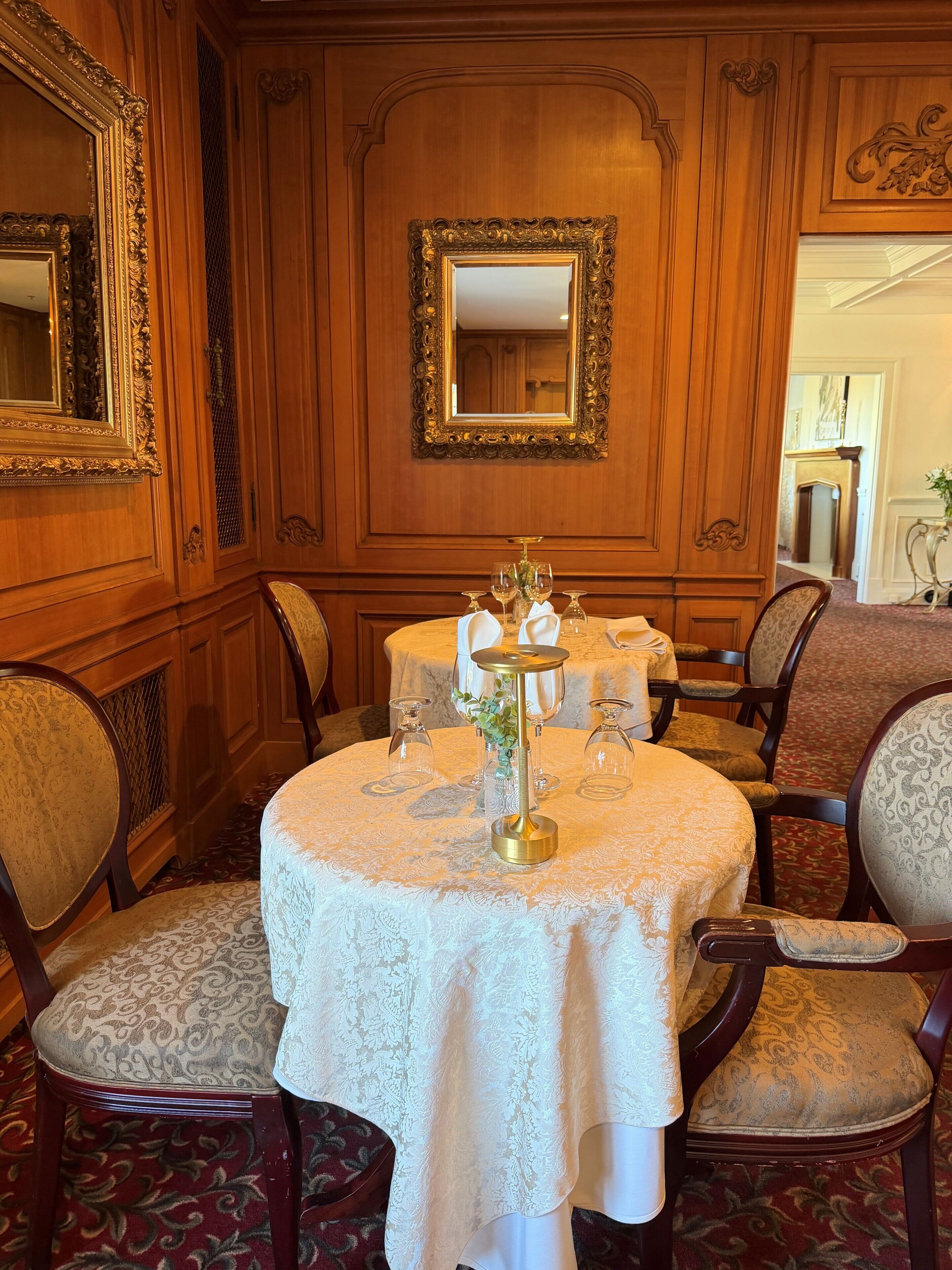 A dining room with a round table, chairs, and a mirror on the wall.