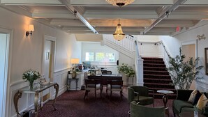 A spacious lobby with a grand chandelier, a staircase, and a reception desk. - Crown Mansion Boutique Hotel & Villas (Qualicum Beach)