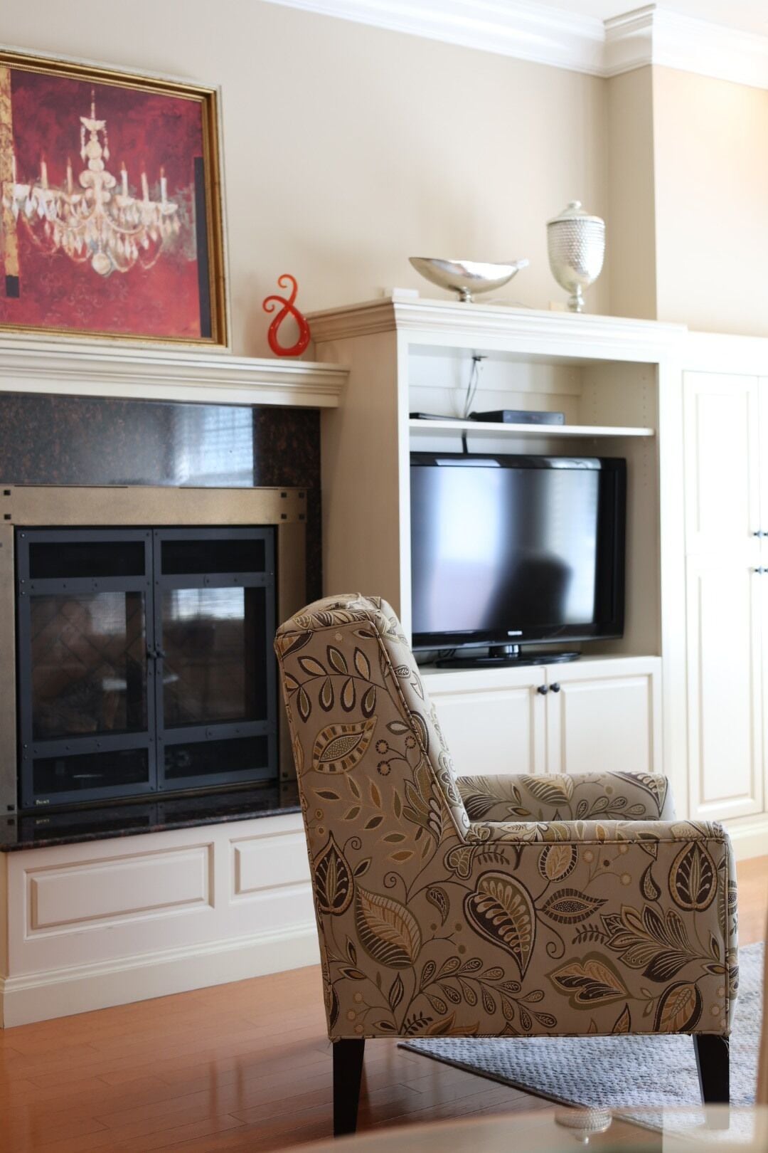 Ein Wohnzimmer mit Kamin, Fernseher und einem gemusterten Sessel.