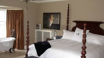 A bedroom with a four-poster bed, a ceiling fan, a large painting, a bathtub, and a window with curtains.