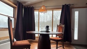 Un coin repas avec une table ronde, deux chaises, une machine à café et un luminaire suspendu.