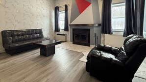 Un salon moderne avec un canapé en cuir noir, une table basse et une cheminée.
