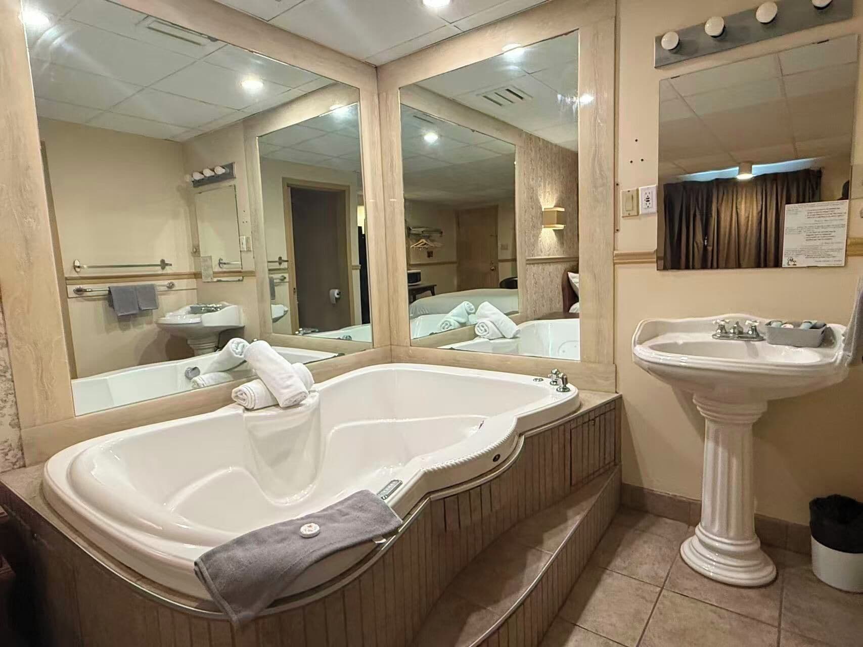 A bathroom with a large bathtub, a sink, and mirrors.
