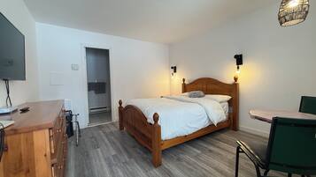 A bedroom with a wooden bed, bedside lamps, a desk, and a chair.