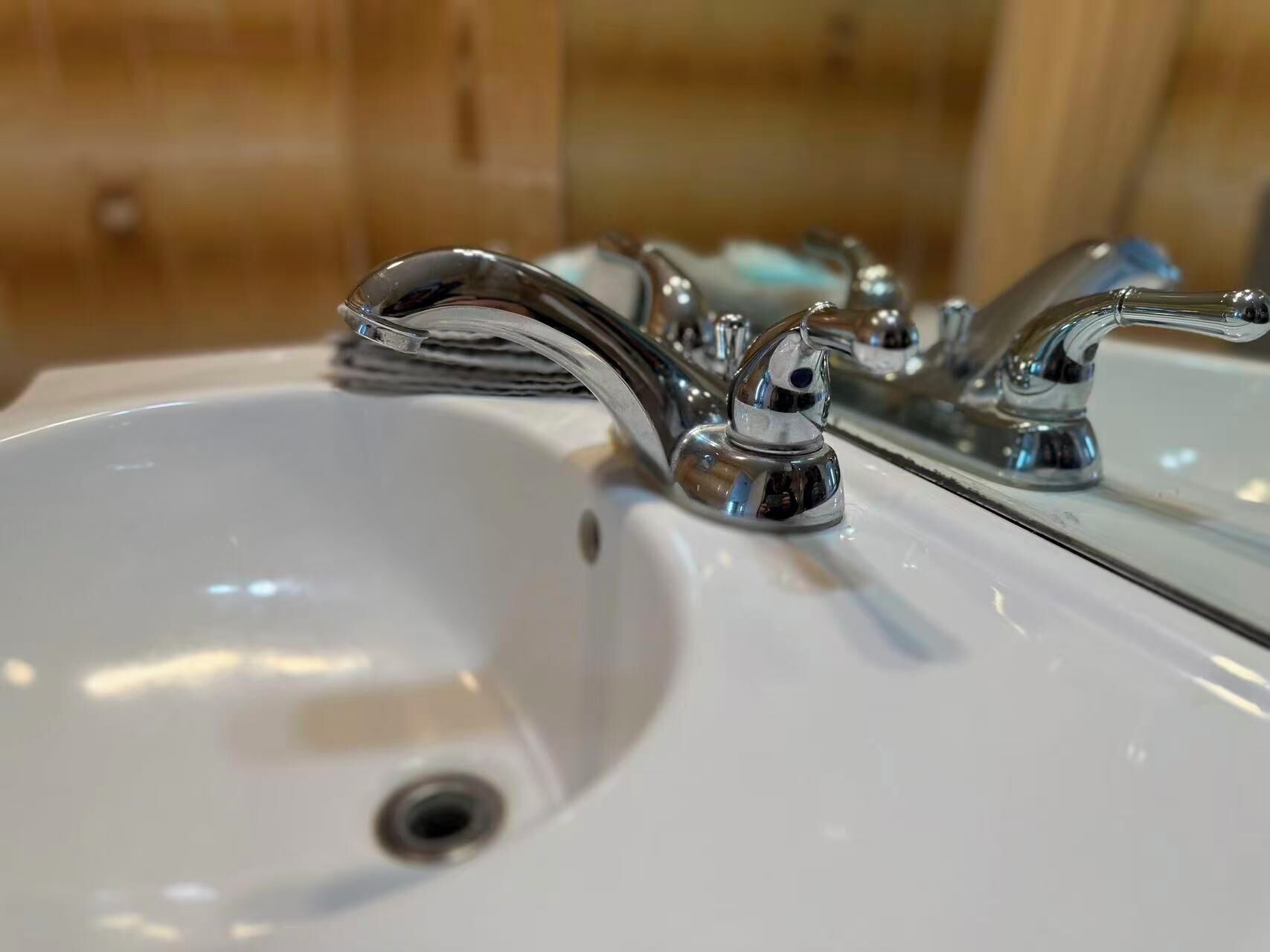 Ein Badezimmerwaschbecken mit chromfarbenen Armaturen und einem Spiegel darüber.
