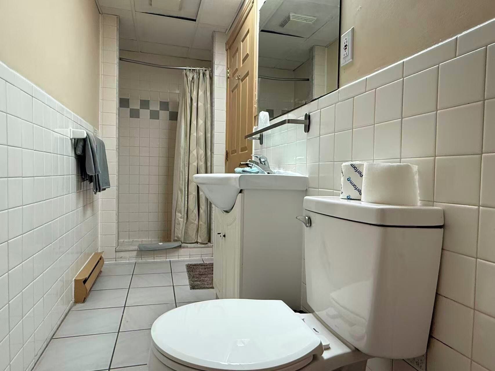A small bathroom with a toilet, sink, and shower.