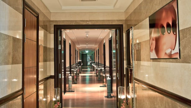 A corridor with a marble floor, wooden doors, and a framed picture on the wall. - Ramee Rose Hotel (Dubai)