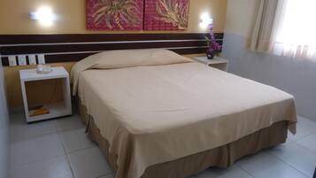 A hotel room with a large bed, a nightstand with a phone, and a wall with two paintings.