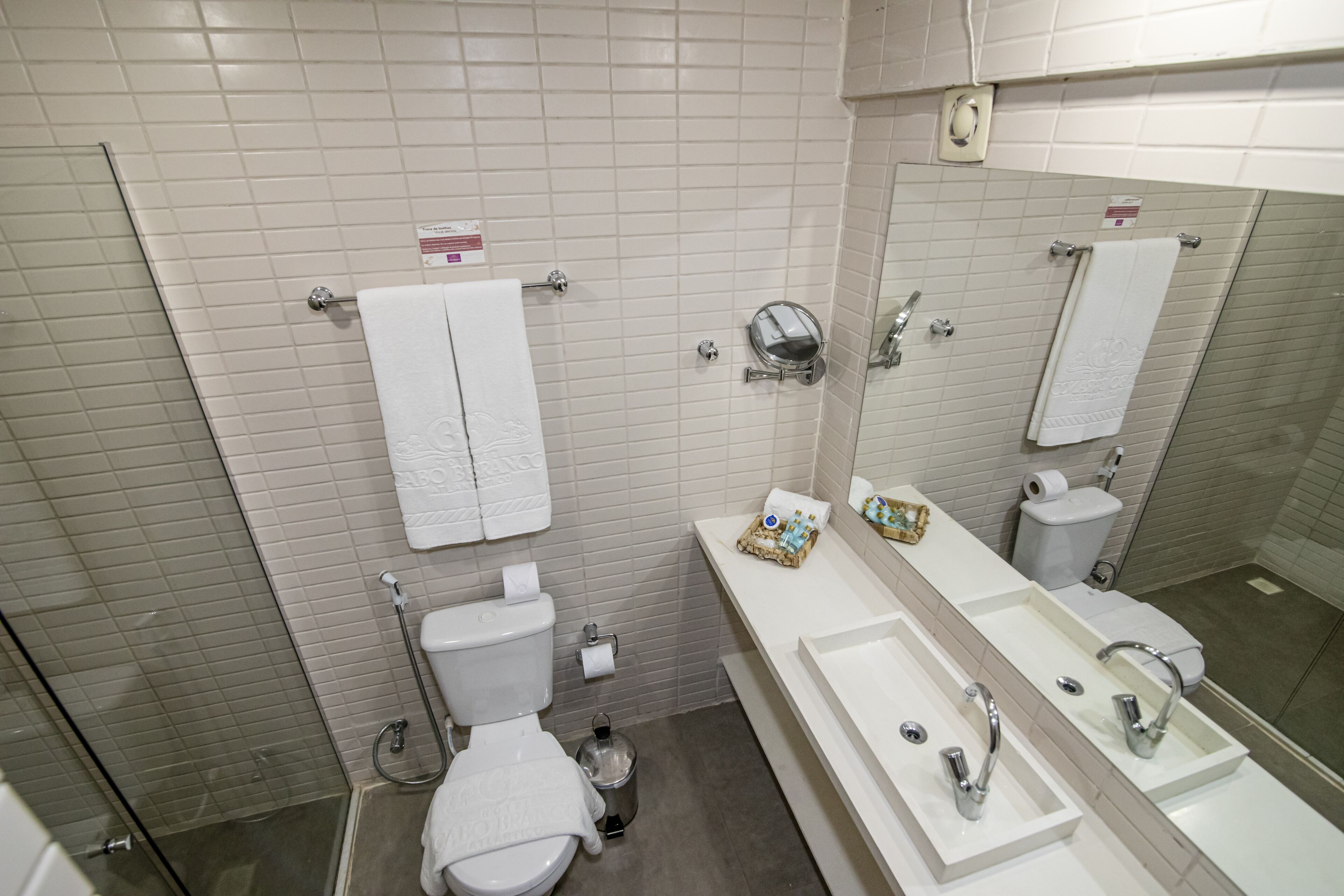 A bathroom with a toilet, bidet, and a large mirror above the sink.