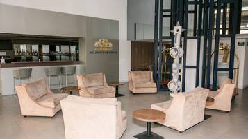 A modern lounge area with sofas and tables, a bar with various bottles, and a decorative sculpture.
