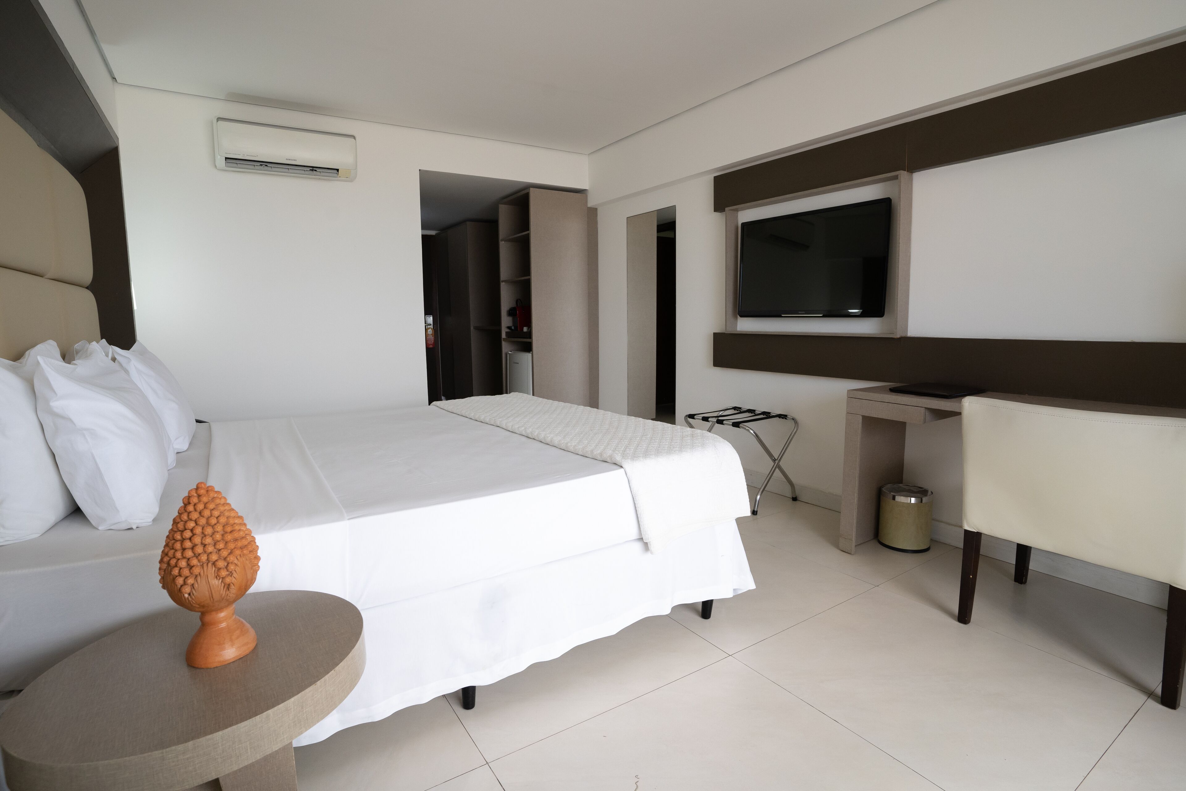 Ein Hotelzimmer mit einem Bett, einem kleinen runden Tisch mit einer Dekoration, einem an der Wand befestigten Fernseher und einem Stuhl.