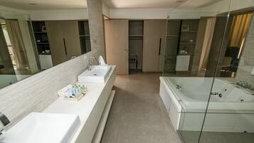 A modern bathroom with a large mirror, two sinks, a bathtub, and a walk-in shower.