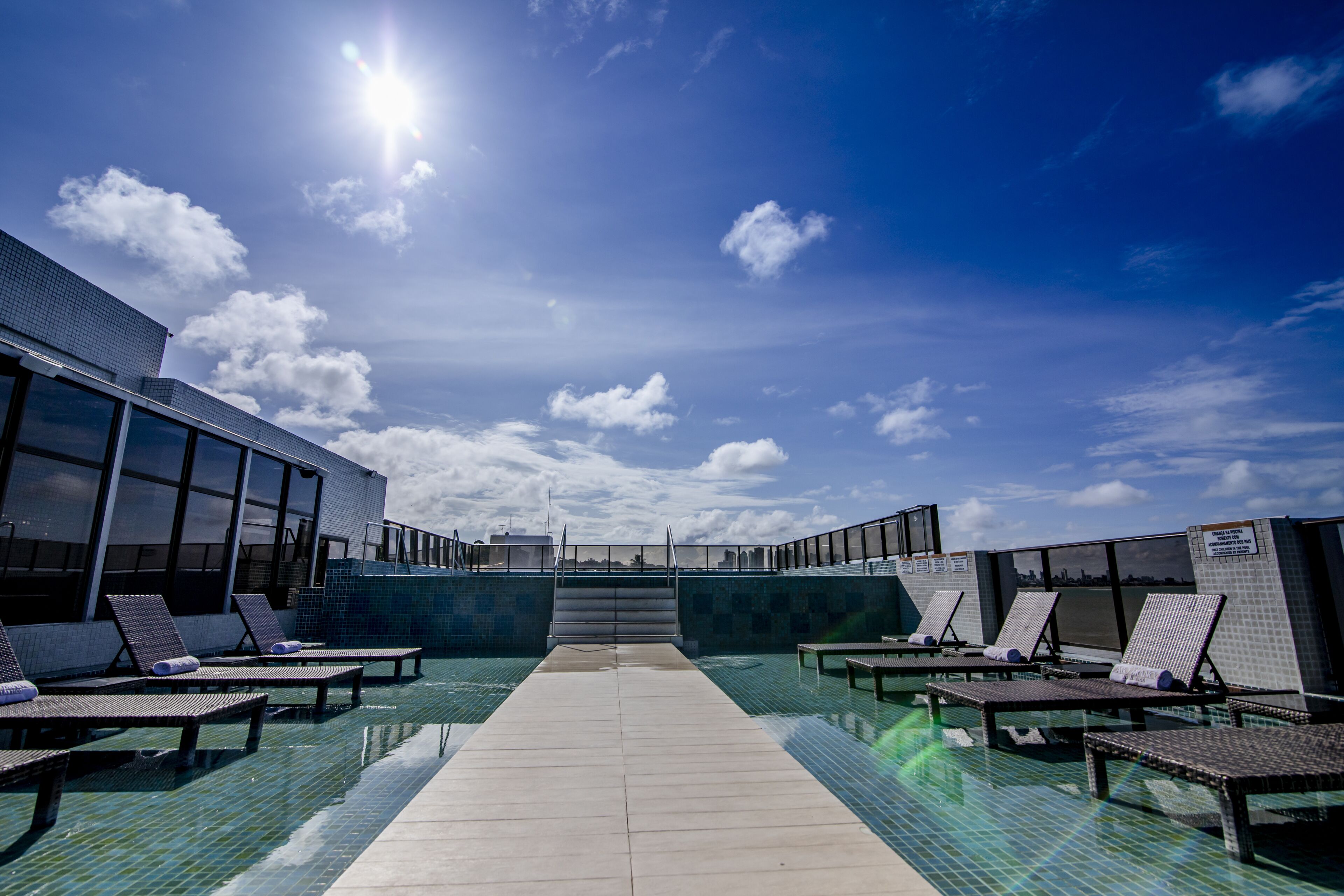A pool area with lounge chairs and a clear sky.