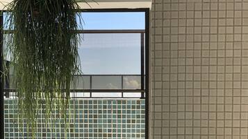 Un bain à remous avec vue sur un mur carrelé et une plante suspendue.