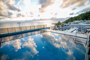 Ein Dachpool im Infinity-Stil mit Blick auf das Meer und einen Sonnenuntergang.