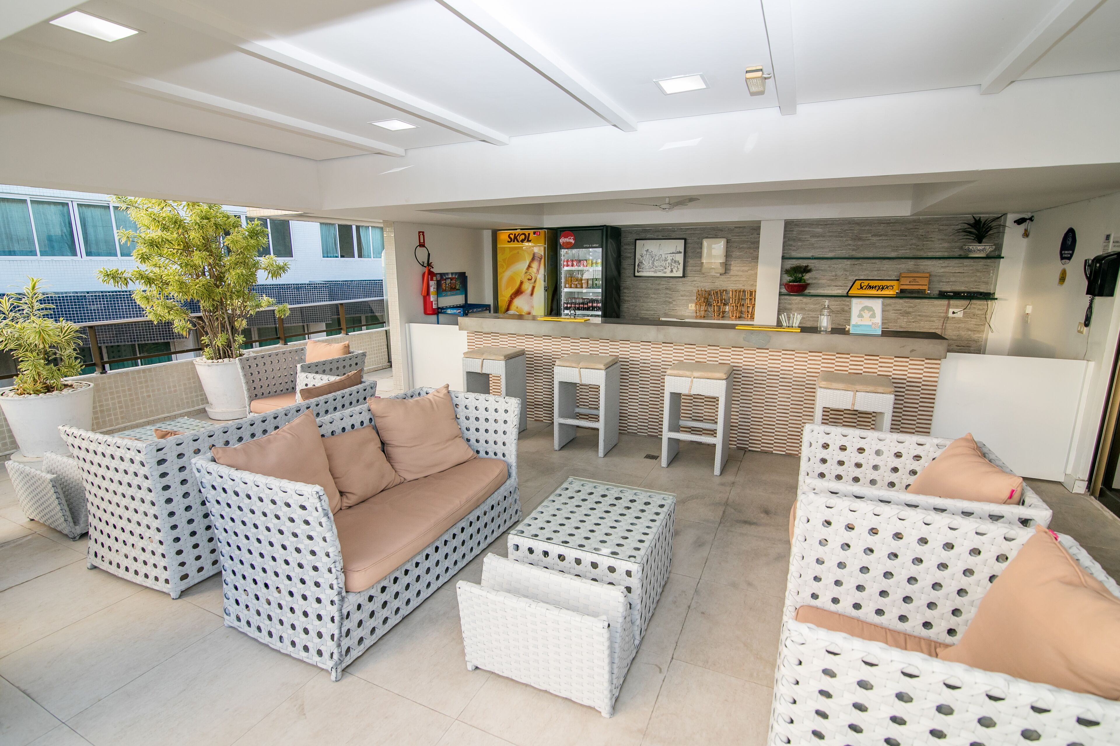 A modern outdoor lounge area with wicker furniture, a bar counter, and potted plants.