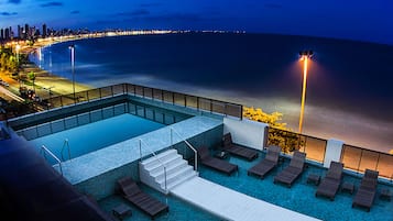 Una piscina al aire libre, sombrillas, sillones reclinables de piscina