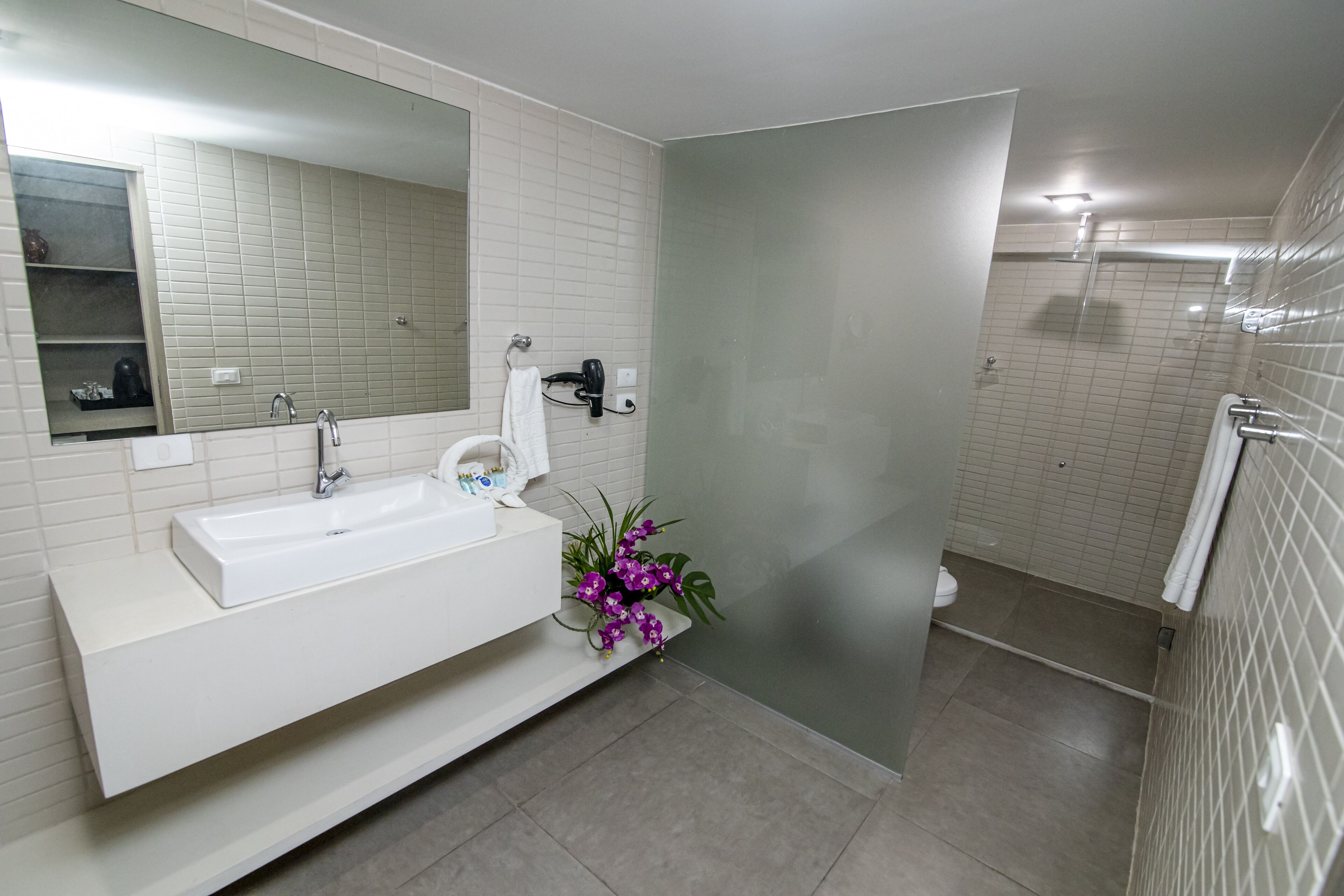 Un baño moderno con un lavamanos, espejo y ducha blancos.