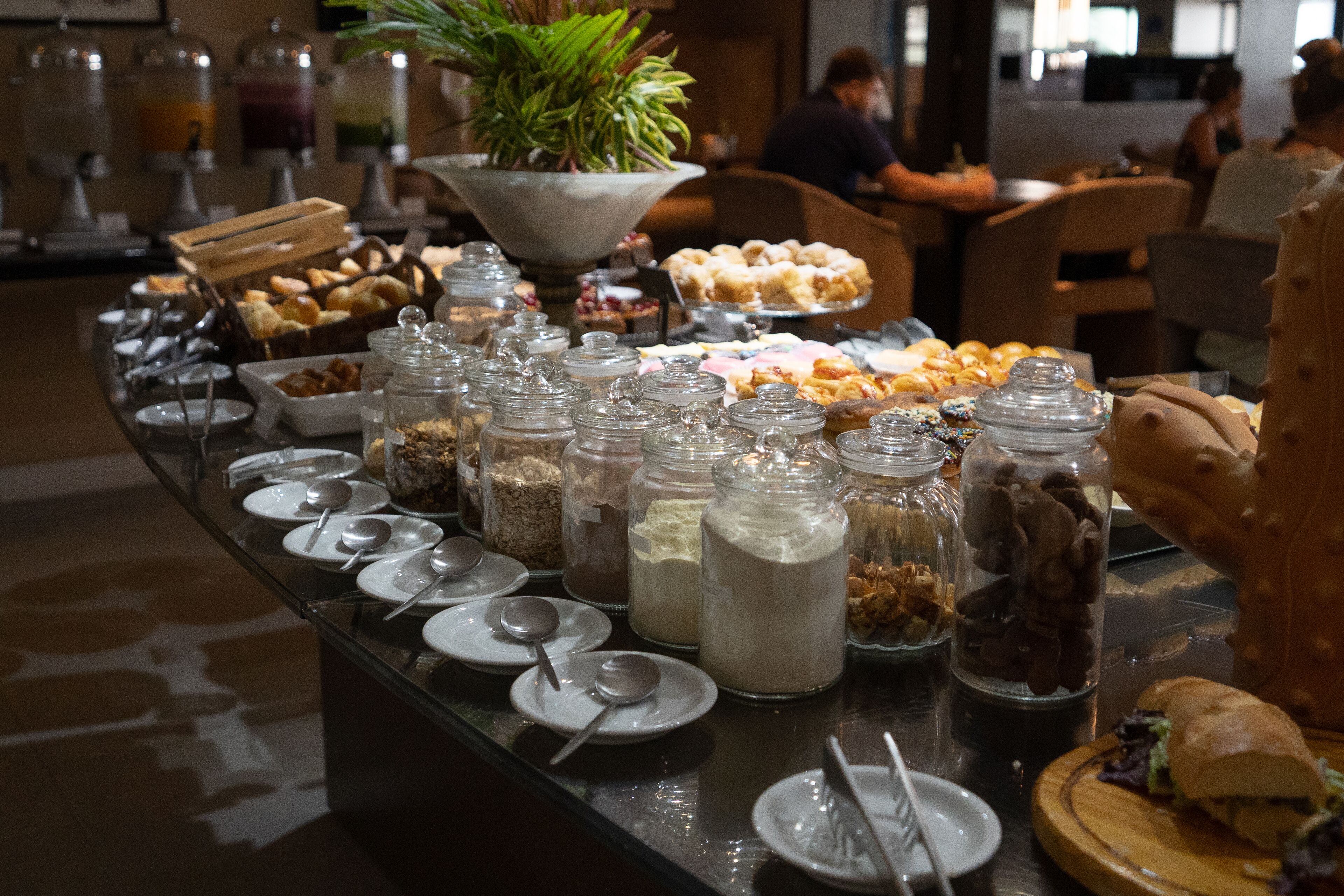 Un buffet con diversi cibi, tra cui pasticceria, frutta e bevande in contenitori di vetro.