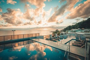 Une piscine à débordement située sur le toit, offrant une vue sur la mer et sur le coucher du soleil.