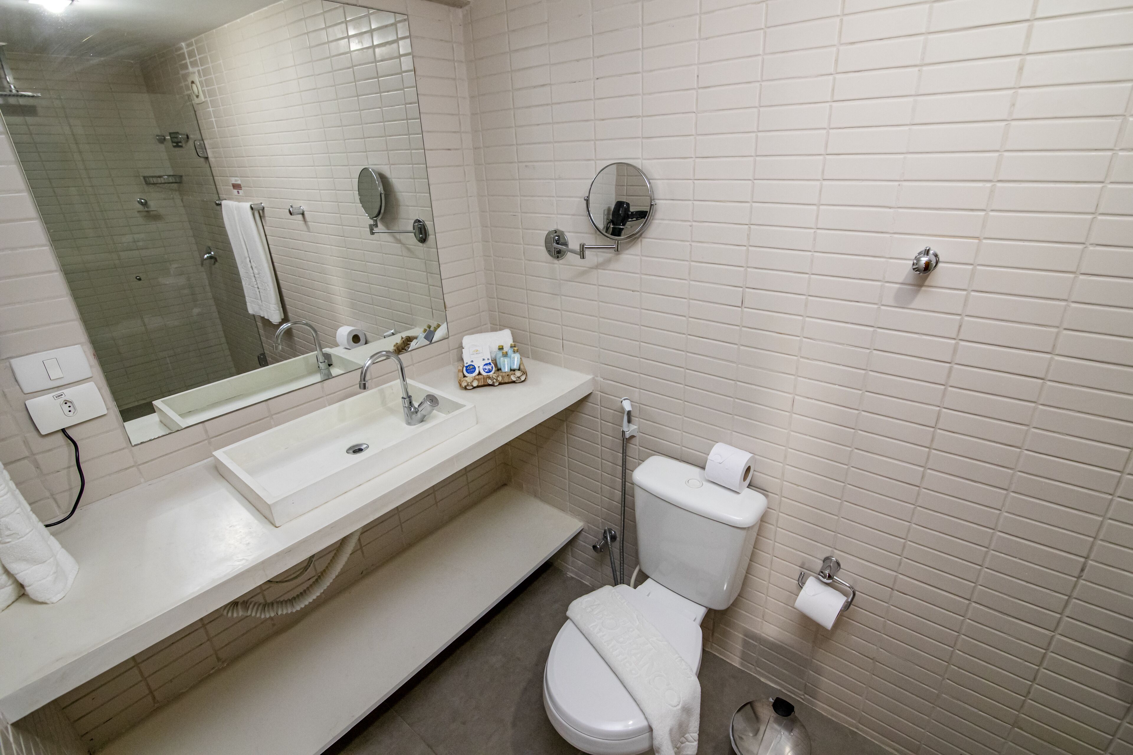 A modern bathroom with a white sink, mirror, and toilet.